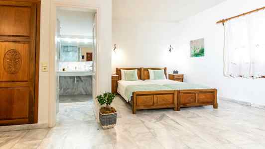 Et soveværelse med to enkeltsenge og en dør, der fører til et badeværelse. (AI-genereret tekst)