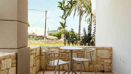 En terrasse med et bord og to stole, omgivet af en lav stenmur. (AI-genereret tekst)