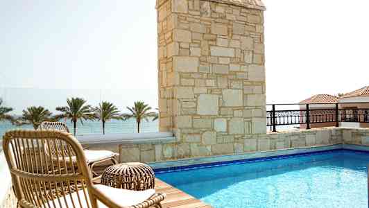 Terrasse med pool, solsenge og udsigt over havet. (AI-genereret tekst)