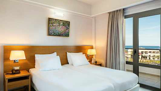 Et værelse med to enkeltsenge, bordlamper og en vinduesdør, der vender ud mod havet. (AI-genereret tekst)