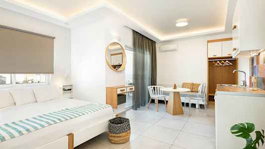 Interiør af et moderne hotelværelse med seng, spisebord og lille køkkenområde. (AI-genereret tekst)