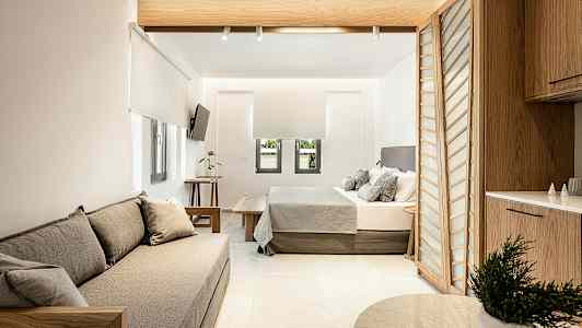 Moderne indrettet hotelsuite med siddeplads, seng og køkkenområde. (AI-genereret tekst)