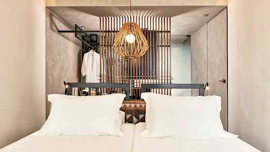 Et hotelværelse med en dobbeltseng og en dekorativ træpanel bag sengen. (AI-genereret tekst)