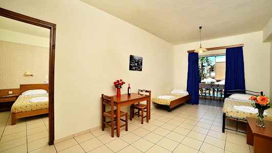 Et hotelværelse med tre senge, spisebord og stor vinduesudgang. (AI-genereret tekst)