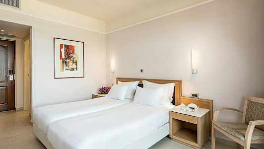 Et hotelværelse med en dobbeltseng, natbord og stol. (AI-genereret tekst)