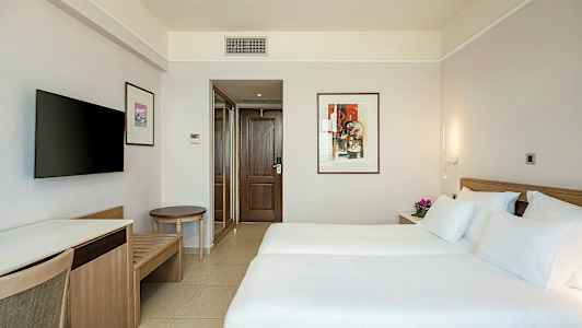 Hotelværelse med to enkeltsenge, dekorativt kunstværk på væggen og tv. (AI-genereret tekst)