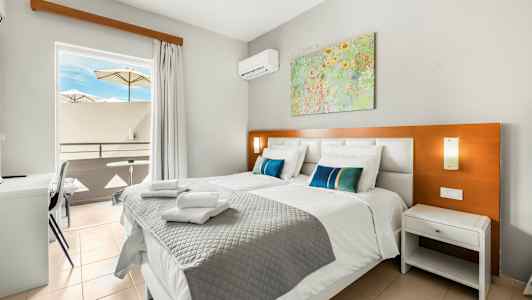 Billede af et hotelværelse med to senge, en altan med parasoller og et maleri på væggen. (AI-genereret tekst)