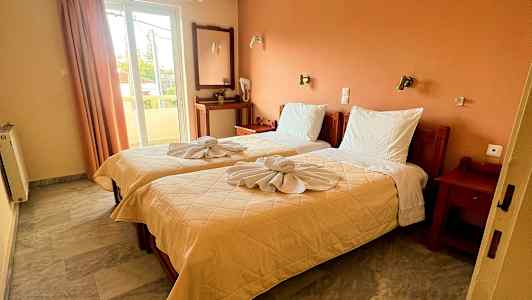 Et hotelværelse med to enkeltsenge, dekoreret med foldede håndklæder. (AI-genereret tekst)