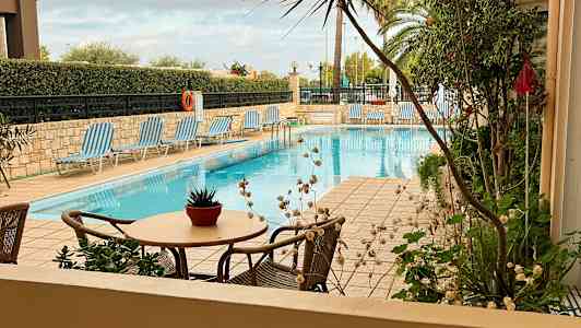 Billede af en udendørs pool med solsenge og bord med en blomsterkrukke. (AI-genereret tekst)