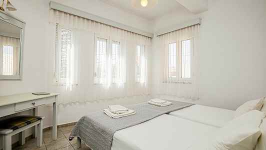 Lyst soveværelse med to enkeltsenge, skrivebord og spejl. (AI-genereret tekst)