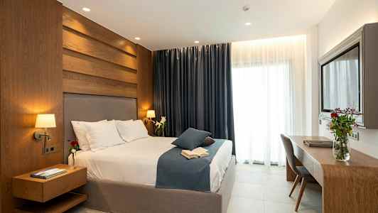 Et moderne soveværelse med en stor seng, træpaneler, mørke gardiner og et skrivebord med en blomsterkrukke. (AI-genereret tekst)