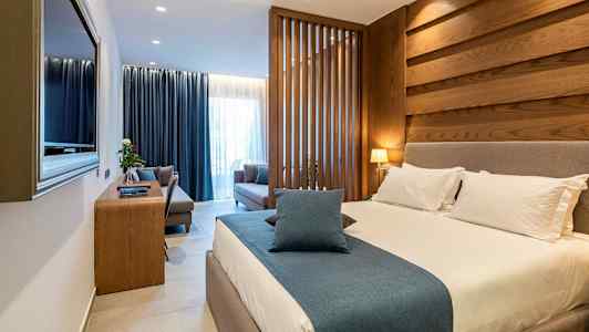 Et hotelværelse med en stor seng, siddeområde og træpaneler. (AI-genereret tekst)