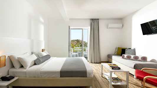 Et moderne hotelværelse med dobbeltseng, sofa, bord og altan med udsigt. (AI-genereret tekst)