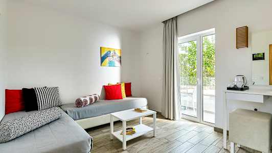 Et værelse med siddeplads og bord, indrettet med lyse farver. (AI-genereret tekst)