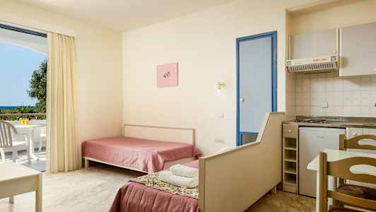 Interiør af et hotelværelse med to enkeltsenge, et lille køkken og en balkon med udsigt. (AI-genereret tekst)