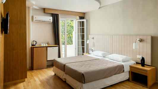 Et hotelværelse med to enkeltsenge, skrivebord, minibar og fransk altan. (AI-genereret tekst)