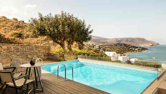 En pool med udsigt over havet og en skråning med huse. (AI-genereret tekst)