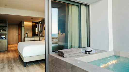 En hotelsuite med et soveværelse og en udendørs jacuzzi. (AI-genereret tekst)