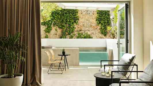 Moderne værelse med siddeområde og udsigt til privat pool og væg med klatreplante. (AI-genereret tekst)