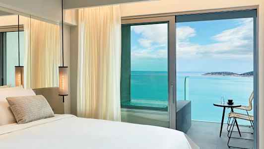 Hotelværelse med havudsigt gennem altandøren. (AI-genereret tekst)