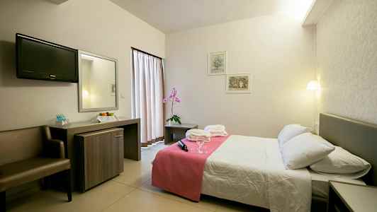 Hotelværelse med dobbeltseng, natbord og skrivebord. (AI-genereret tekst)