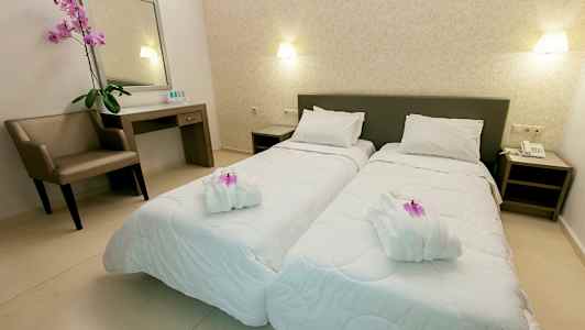 To enkeltsenge i et velorganiseret hotelværelse med en stol, et skrivebord og dekorative elementer. (AI-genereret tekst)