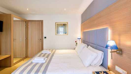 Et hotelværelse med en dobbeltseng, trædetaljer, blå lamper og et spejlskab. (AI-genereret tekst)