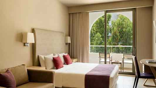 Hotelværelse med dobbeltseng, sofa og udgang til altan. (AI-genereret tekst)