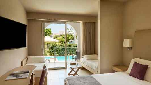 Et hotelværelse med en dobbeltseng, et skriveplads og en ekstra seng. Udenfor ses en terrasse og en pool. (AI-genereret tekst)