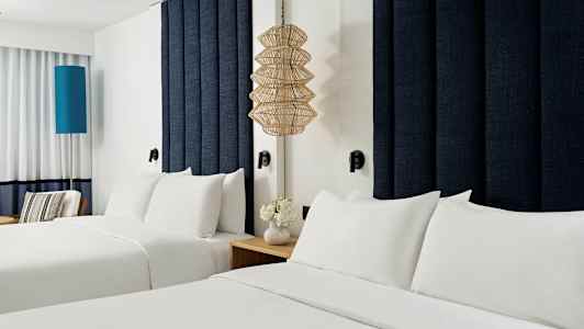 To senge med hvidt sengetøj på et hotelværelse. (AI-genereret tekst)