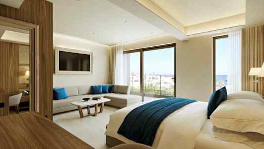 Moderne hotelværelse med en dobbeltseng, siddeområde og store vinduer med udsigt over havet. (AI-genereret tekst)