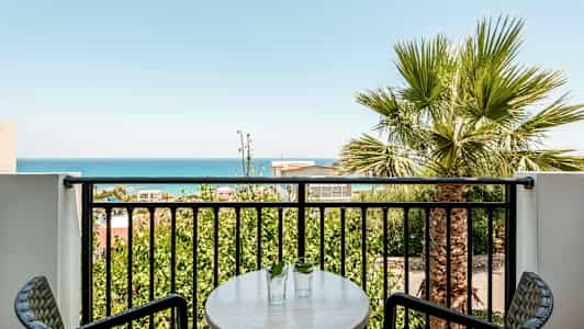 En altan med udsigt over havet og grønne træer. (AI-genereret tekst)