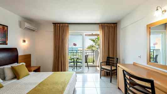 Soveværelse med dobbeltseng og udsigt til en altan med stole og bord. (AI-genereret tekst)