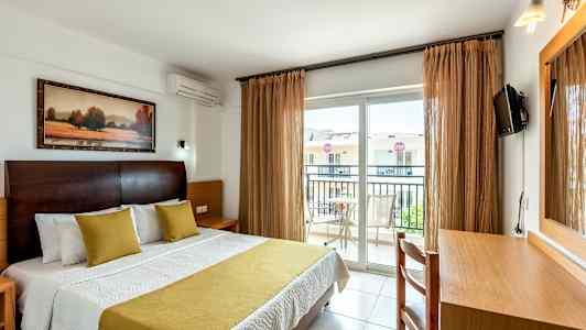 Interiør af hotelværelse med en seng, skrivebord og balkon. (AI-genereret tekst)