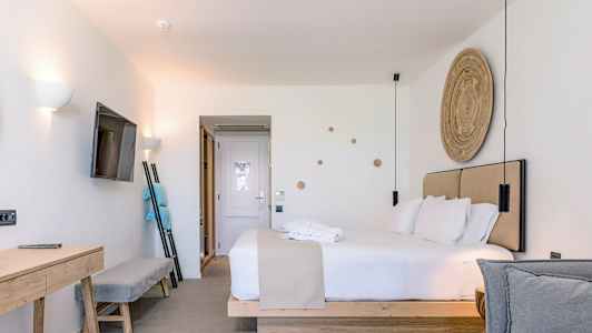 Moderne hotelværelse med dobbeltseng, vægmonteret tv og skrivebord. (AI-genereret tekst)