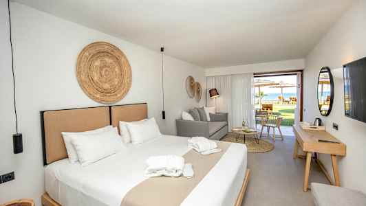 En hotelsuite med dobbeltseng, siddeplads og adgang til en møbleret terrasse. (AI-genereret tekst)