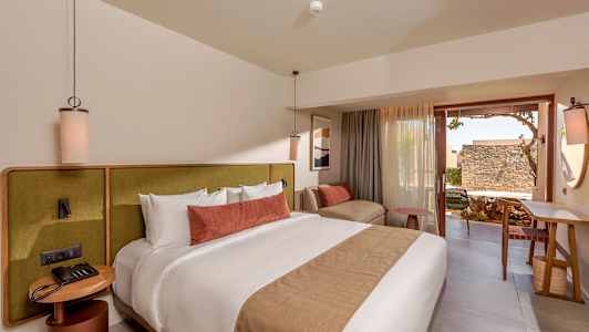 Et moderne hotelværelse med en stor seng, komfortable møbler og en terrasse. (AI-genereret tekst)