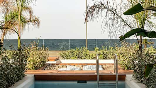 En lille pool med en træhave ved siden af, udsigt over havet og glasrækværk. (AI-genereret tekst)