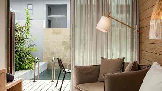 Et rum med en brun lænestol, en gulvlampe og udsigt til en terrasse med pool. (AI-genereret tekst)