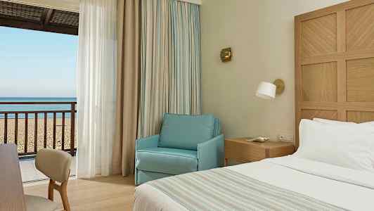 Hotelværelse med udsigt til sandstrand og hav. (AI-genereret tekst)