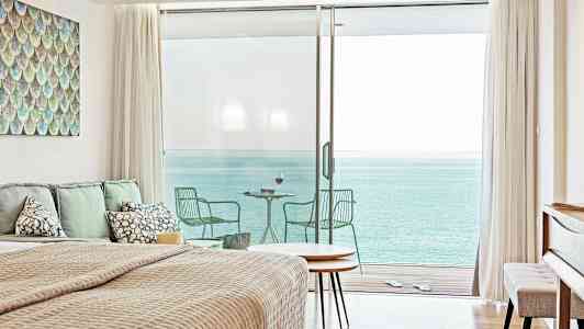 Et soveværelse med havudsigt gennem store glasdøre, der fører til en altan. (AI-genereret tekst)