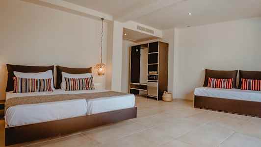 Et hotelværelse med en stor seng, dekorative puder og en åben garderobe. (AI-genereret tekst)