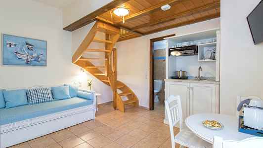 Et rum med træmøbler, en spiraltrappe, en sofa og et bord. (AI-genereret tekst)