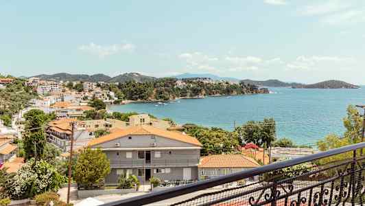 Udsigt over en kystby med røde tage og havet i baggrunden. (AI-genereret tekst)