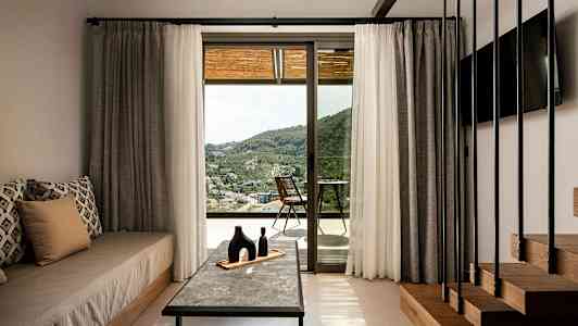 Rum med indretning og udsigt over landskabet gennem en glasdør. (AI-genereret tekst)