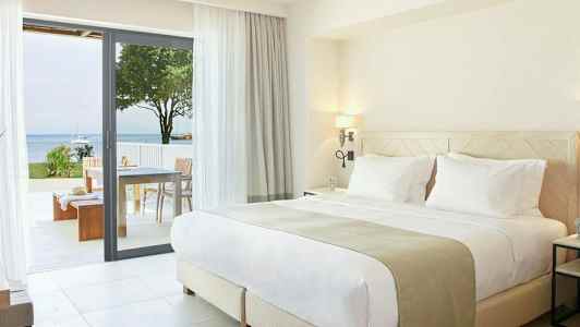 Moderne soveværelse med dobbeltseng og udgang til terrasse med havudsigt. (AI-genereret tekst)