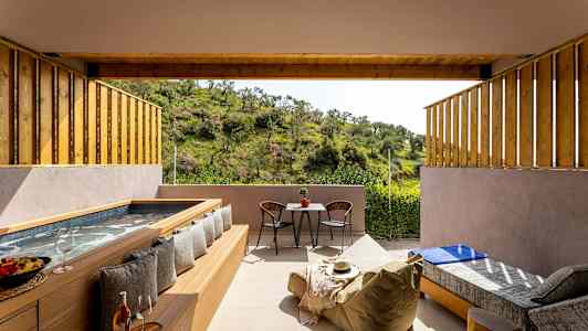 En gårdhave med badekar, siddepladser og udsigt til grøn natur. (AI-genereret tekst)