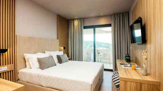 Hotelværelse med en stor seng, moderne indretning og udsigt til en terrasse. (AI-genereret tekst)