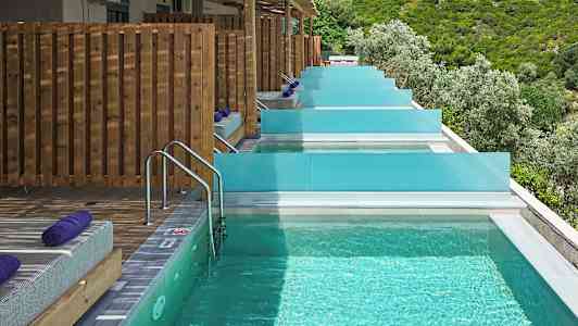 Private pools med solsenge og udsigt over frodigt landskab. (AI-genereret tekst)