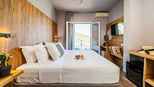 Hotelværelse med en dobbeltseng, udsmykket med træpaneler og en balkon med udsigt. (AI-genereret tekst)